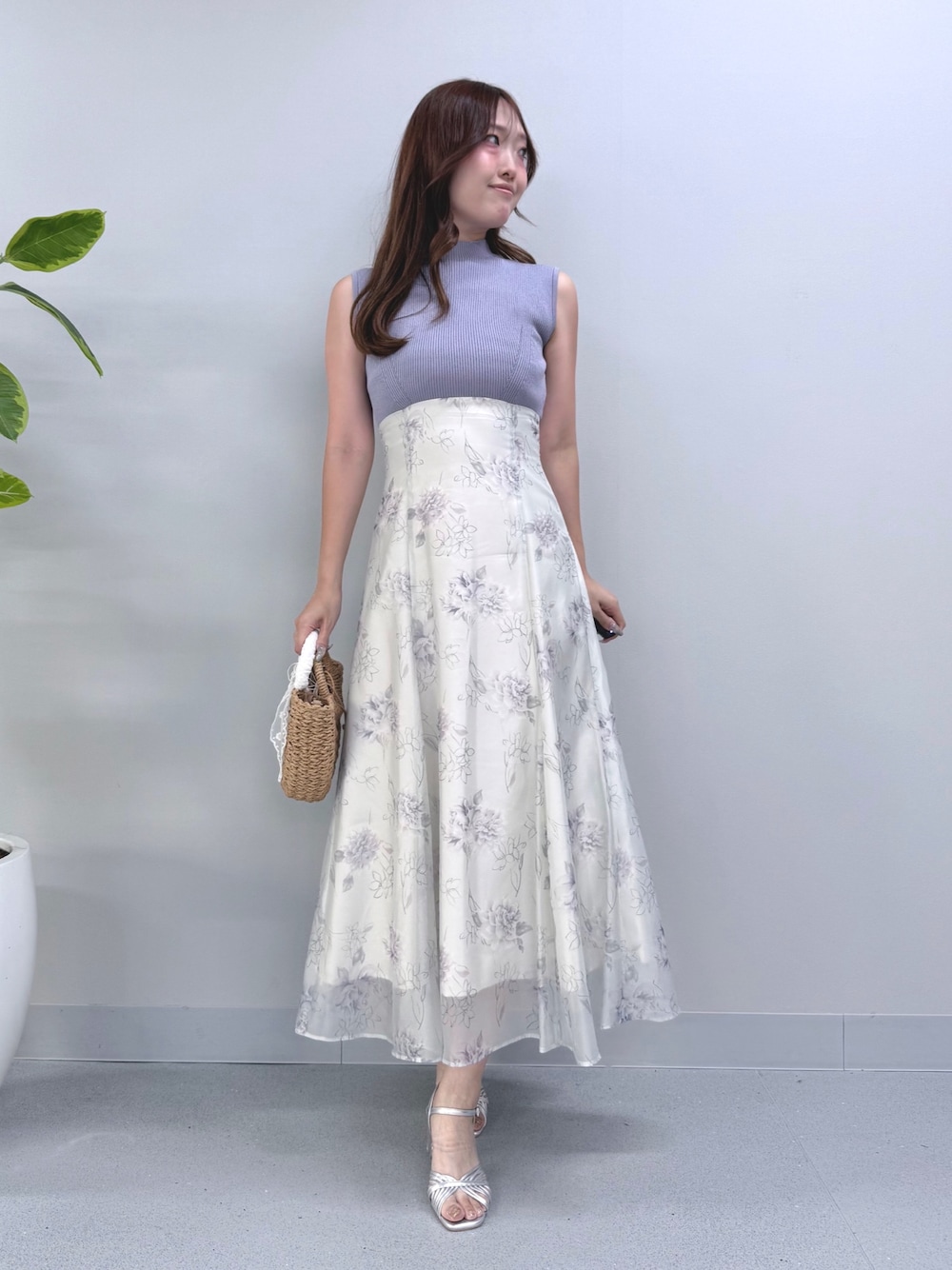 パープル系のワンピース、ベージュ系のハンドバッグ、シルバー系のサンダルを着用したレディースの夏コーディネートの1枚目の写真