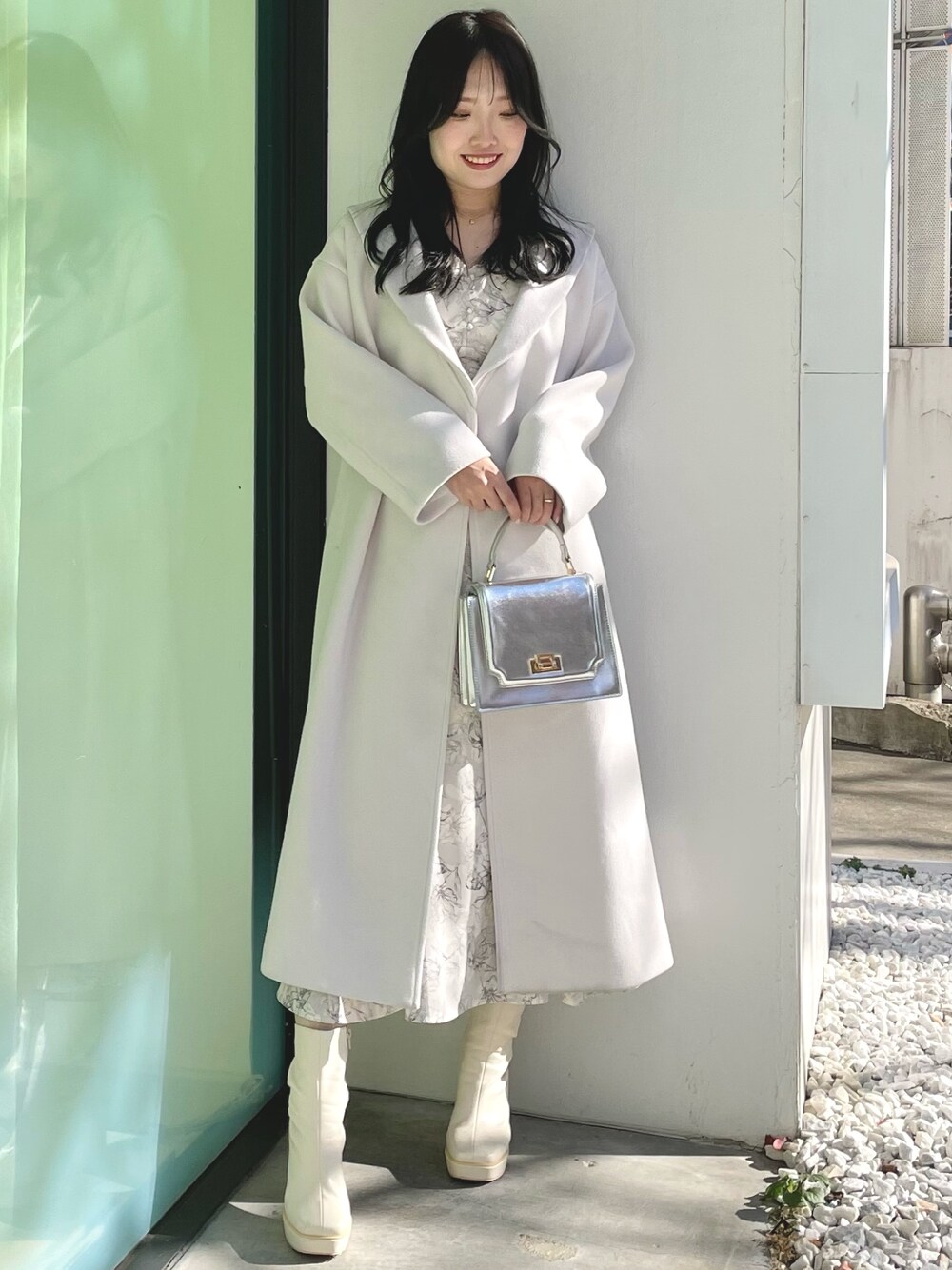 シルバー系のハンドバッグ、ホワイト系のブーツ、ホワイト系のチェスターコートを着用したレディースの冬コーディネートの1枚目の写真