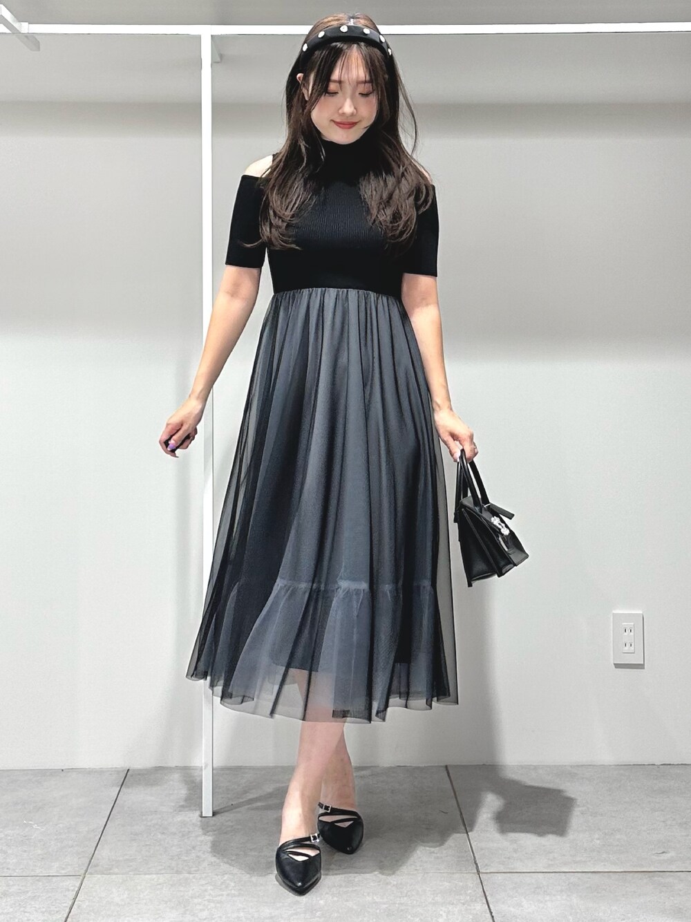 ブラック系のワンピース、ブラック系のショルダーバッグ、ブラック系のパンプスを着用したレディースの夏コーディネートの1枚目の写真