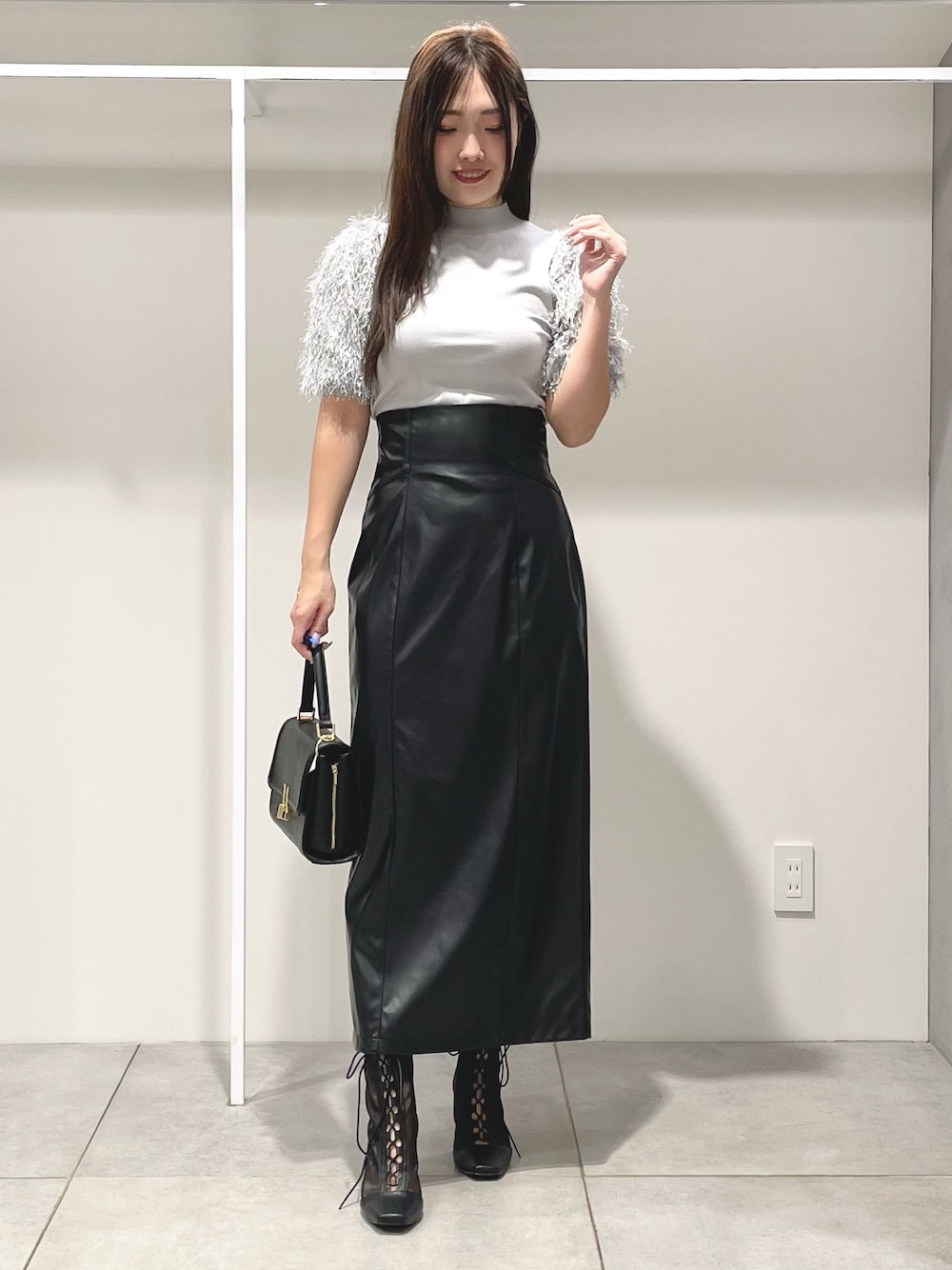 グレー系のニット/セーター、ブラック系のスカート、ブラック系のショルダーバッグを着用したレディースの秋コーディネートの1枚目の写真