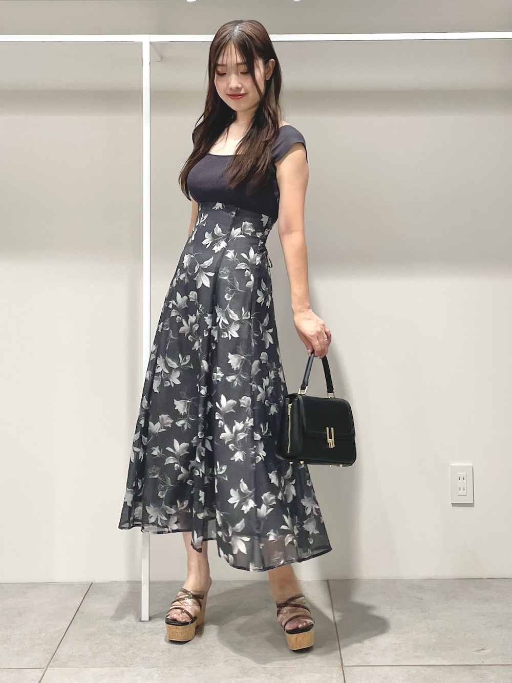ブラック系のショルダーバッグ、ブラック系のサンダル、グレー系のワンピースを着用したレディースの夏コーディネートの1枚目の写真