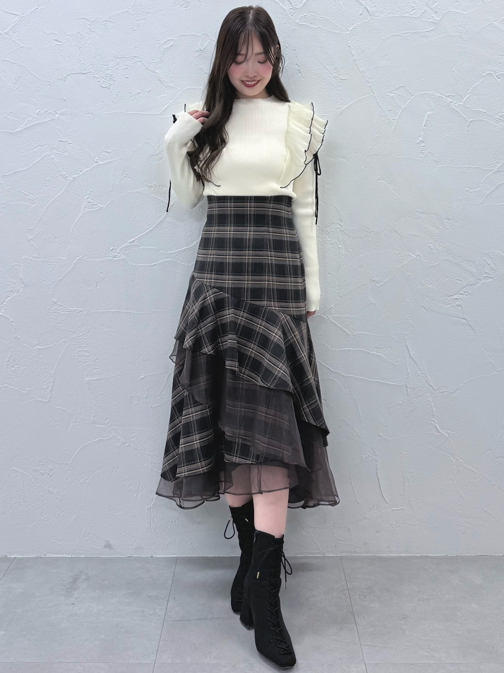 グレー系のスカート、ブラック系のブーツ、ホワイト系のニット/セーターを着用したレディースの秋コーディネートの1枚目の写真