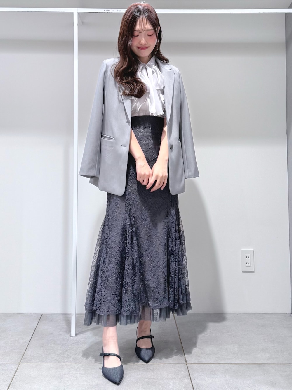 グレー系のシャツ/ブラウス、グレー系のスカート、ブルー系のパンプスを着用したレディースの春コーディネートの1枚目の写真