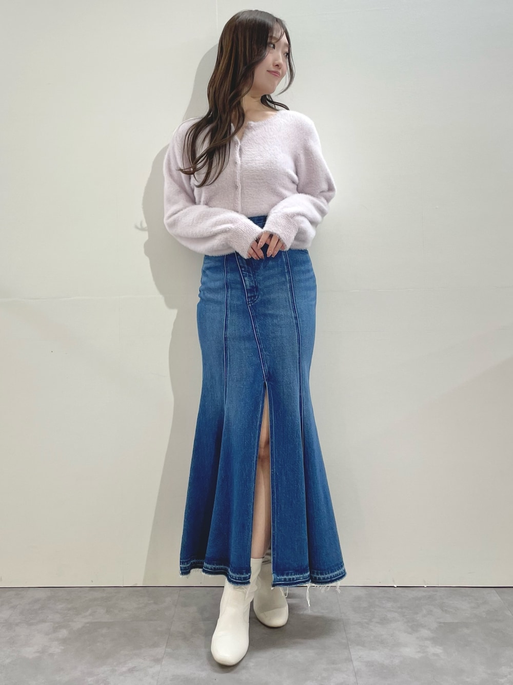 ピンク系のカーディガン/ボレロ、ブルー系のスカート、ホワイト系のブーツを着用したレディースの冬コーディネートの1枚目の写真