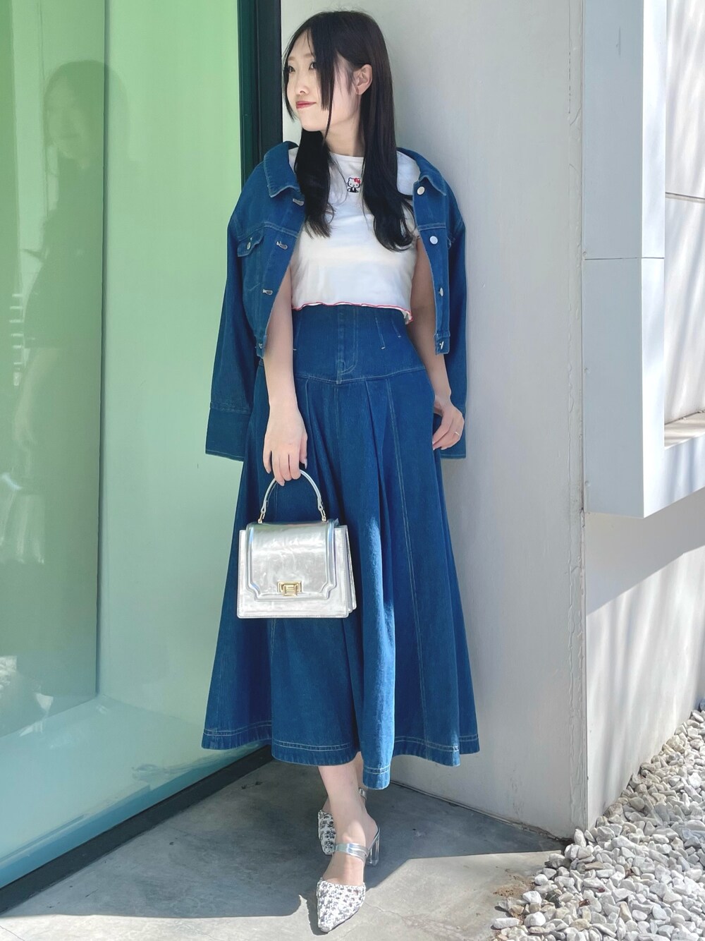 ブルー系のスカート、シルバー系のハンドバッグ、シルバー系のパンプスを着用したレディースの春コーディネートの1枚目の写真
