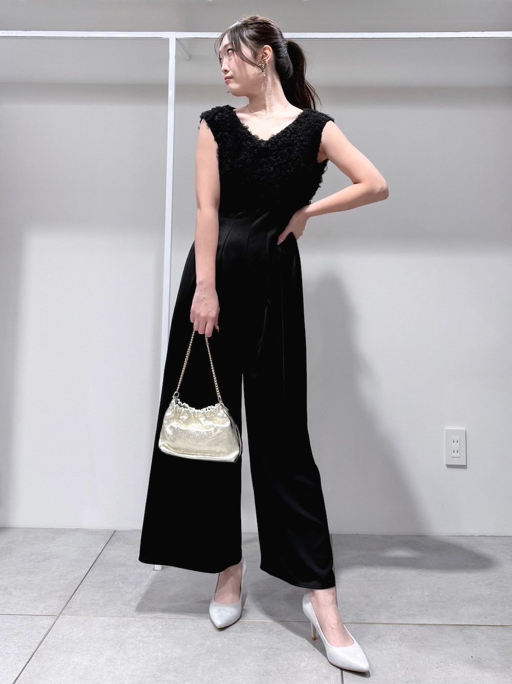 ブラック系のドレス、ゴールド系のショルダーバッグ、シルバー系のパンプスを着用したレディースの冬コーディネートの1枚目の写真