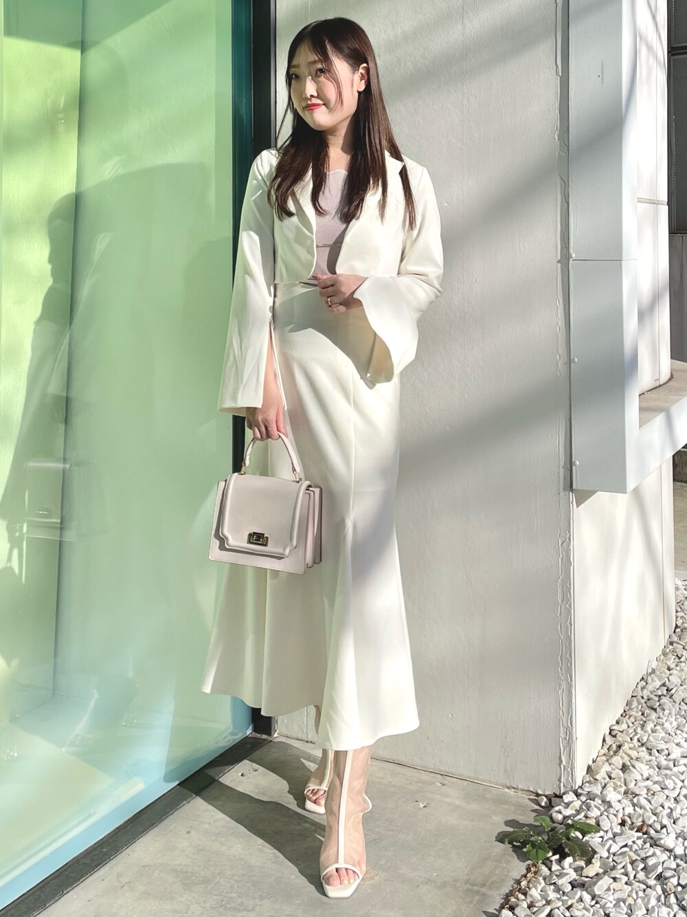 ピンク系のニット/セーター、ホワイト系のテーラードジャケット、ホワイト系のスカートを着用したレディースの春コーディネートの1枚目の写真