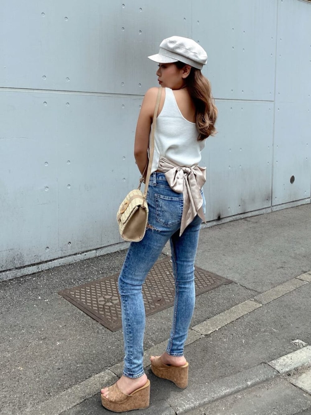 ブルー系のデニムパンツ、ベージュ系のサンダル、ホワイト系のタンクトップを着用したレディースの夏コーディネートの1枚目の写真