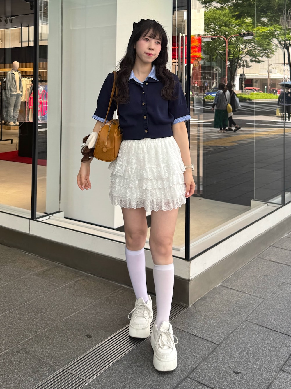 ブルー系のニット/セーター、ホワイト系のスカート、ホワイト系のスニーカーを着用したレディースの春コーディネートの1枚目の写真