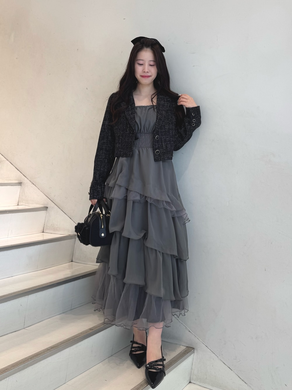 ブラック系のテーラードジャケット、グレー系のワンピース、ブラック系のショルダーバッグを着用したレディースの冬コーディネートの1枚目の写真