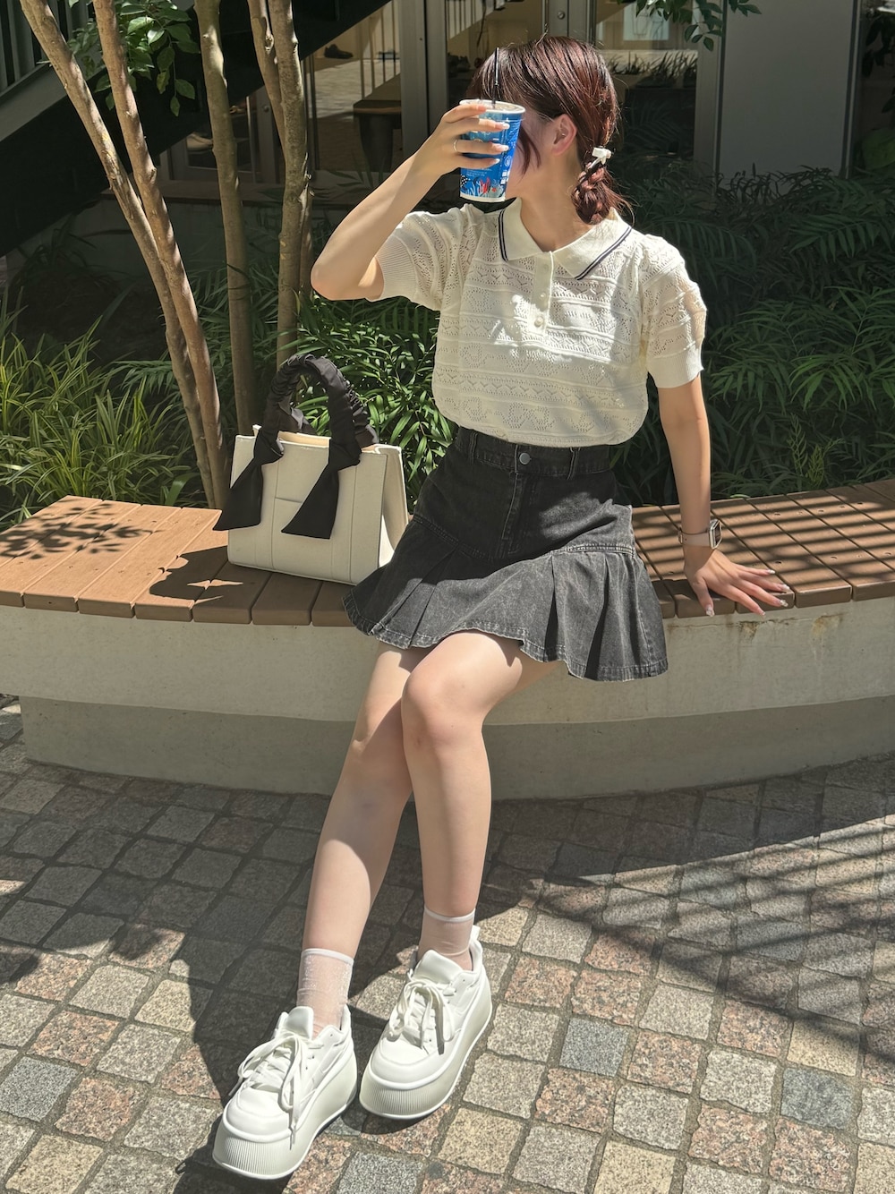 ホワイト系のニット/セーター、ブラック系のスカート、ホワイト系のスニーカーを着用したレディースの夏コーディネートの1枚目の写真