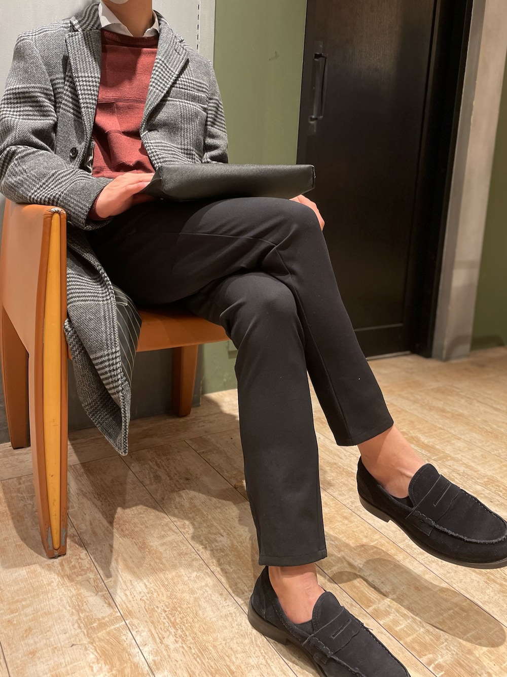 グレー系のチェスターコート、レッド系のニット/セーター、ホワイト系のシャツ/ブラウスを着用したメンズの冬コーディネートの1枚目の写真