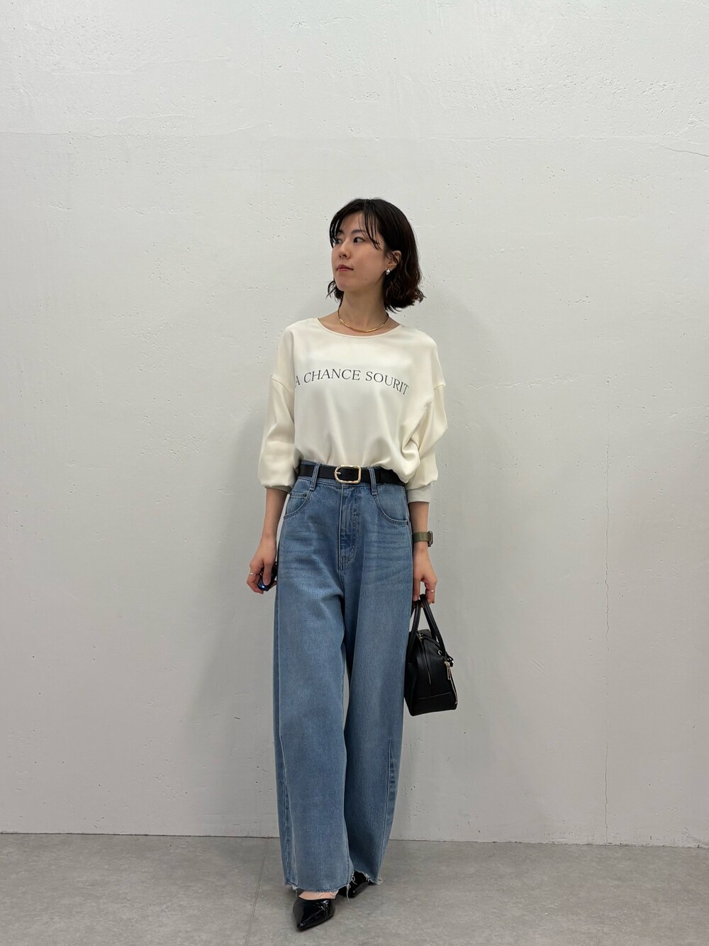ブルー系のデニムパンツ、ブラック系のパンプス、ブラック系のボストンバッグを着用したレディースの秋コーディネートの1枚目の写真