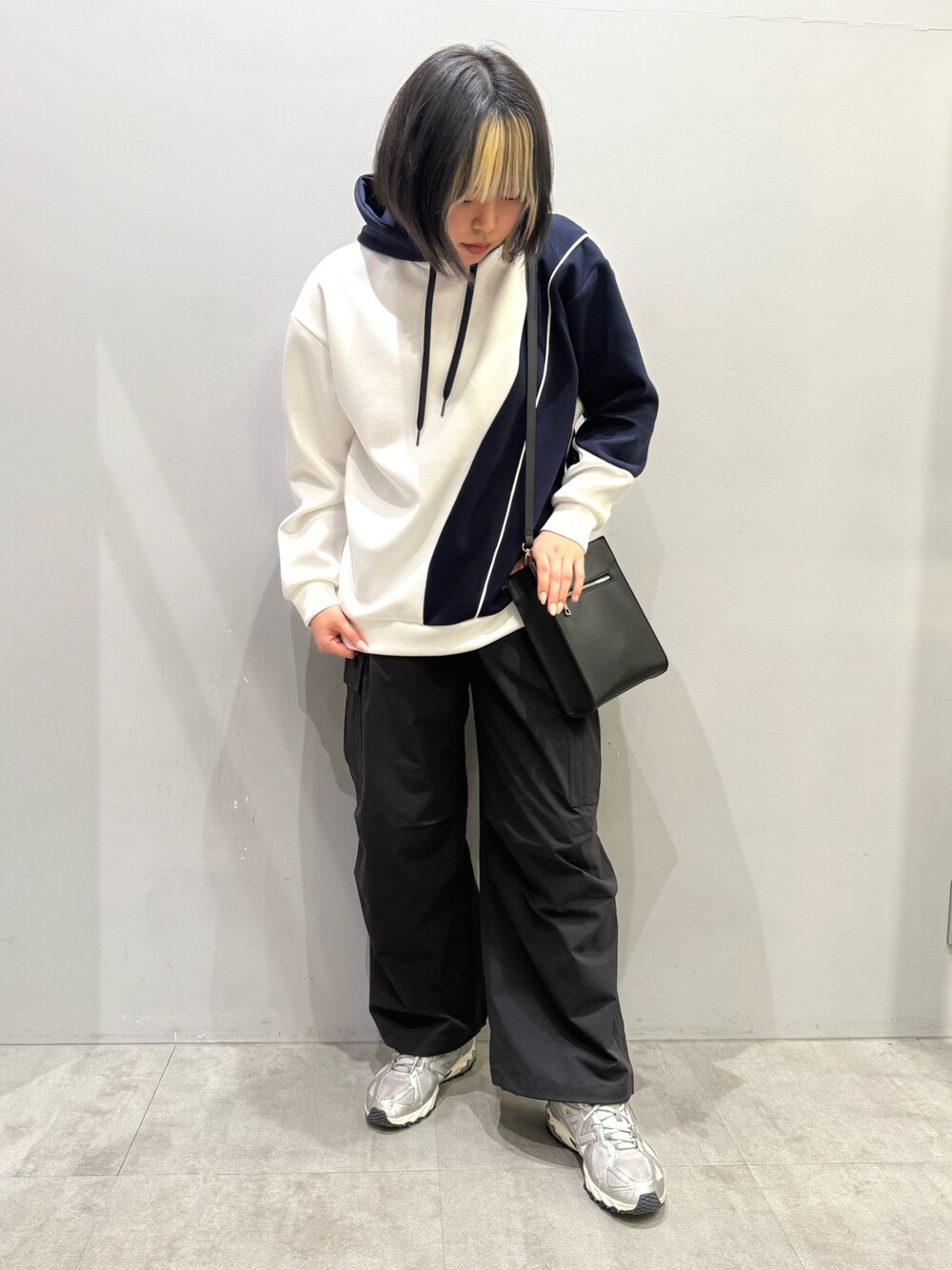 ブラック系のカーゴパンツ、ホワイト系のパーカー、ブラック系のショルダーバッグを着用したレディースの春コーディネートの1枚目の写真