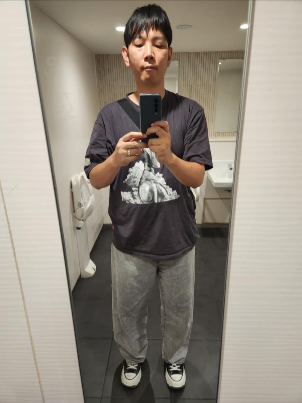 グレー系のTシャツ/カットソー、グレー系のデニムパンツ、ブラック系のスニーカーを着用したメンズの秋コーディネートの1枚目の写真