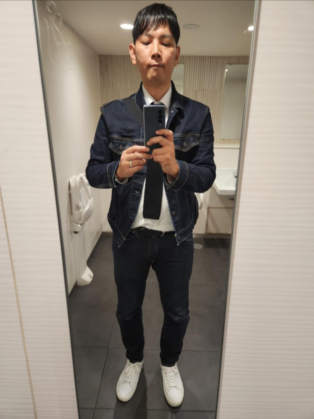 ブルー系のデニムジャケット、ホワイト系のビジネスシャツ、ブラック系のネクタイを着用したメンズの冬コーディネートの1枚目の写真