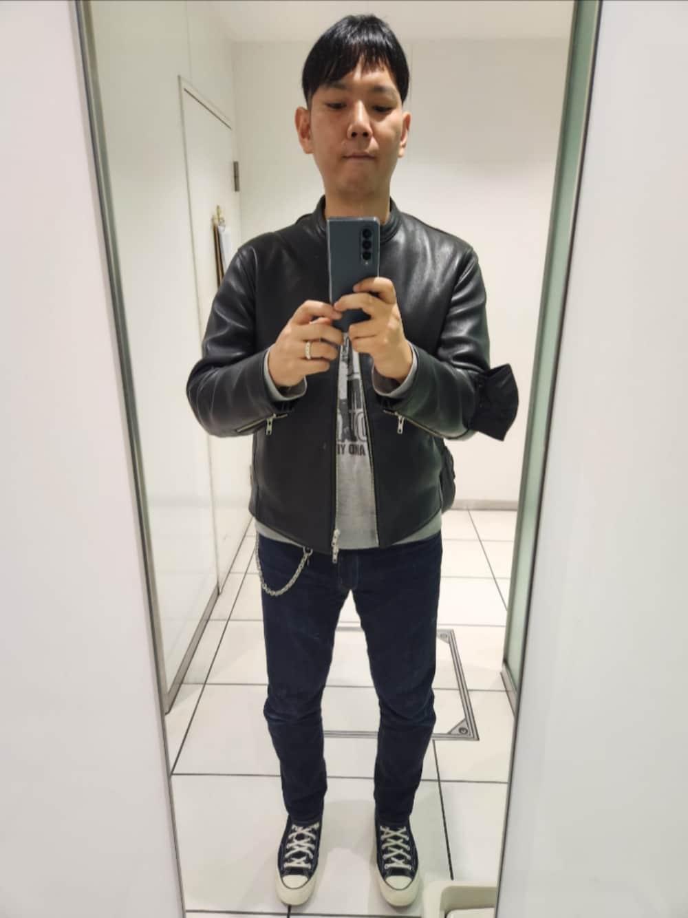 ブラック系のライダースジャケット、グレー系のスウェット、ブルー系のデニムパンツを着用したメンズの秋コーディネートの1枚目の写真