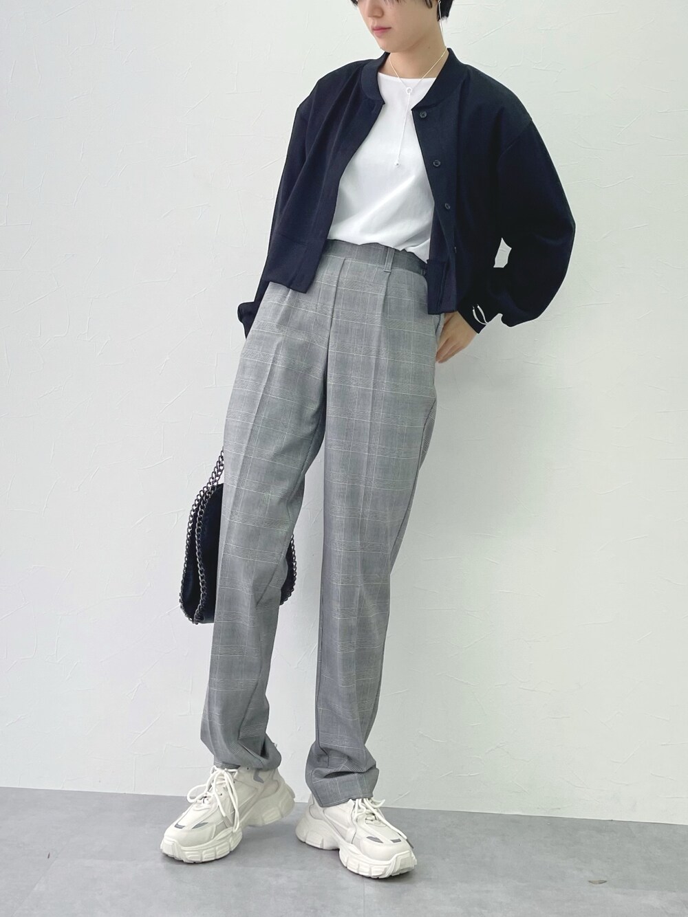 グレー系のパンツ、ブラック系のワンピース、ホワイト系のTシャツ/カットソーを着用したレディースの春コーディネートの1枚目の写真