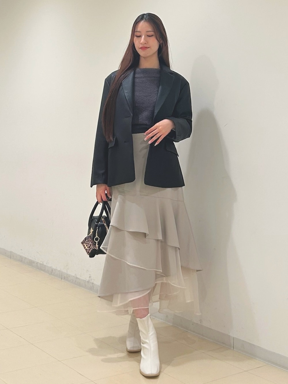 ベージュ系のスカート、グレー系のニット/セーター、ブラック系のハンドバッグを着用したレディースの秋コーディネートの1枚目の写真