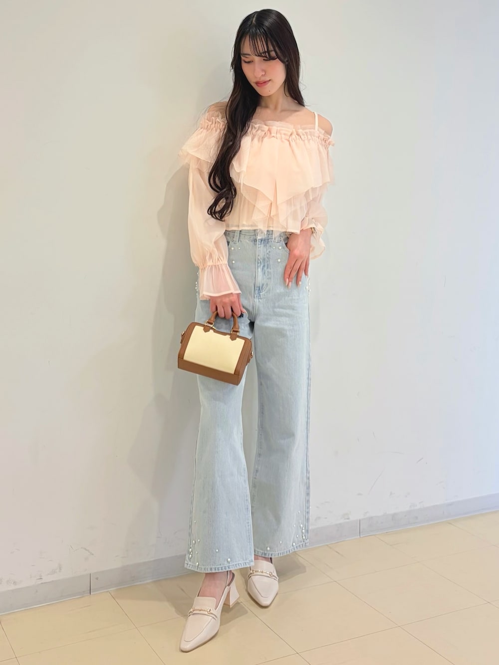 ピンク系のシャツ/ブラウス、ブルー系のデニムパンツ、ブラウン系のハンドバッグを着用したレディースの春コーディネートの1枚目の写真