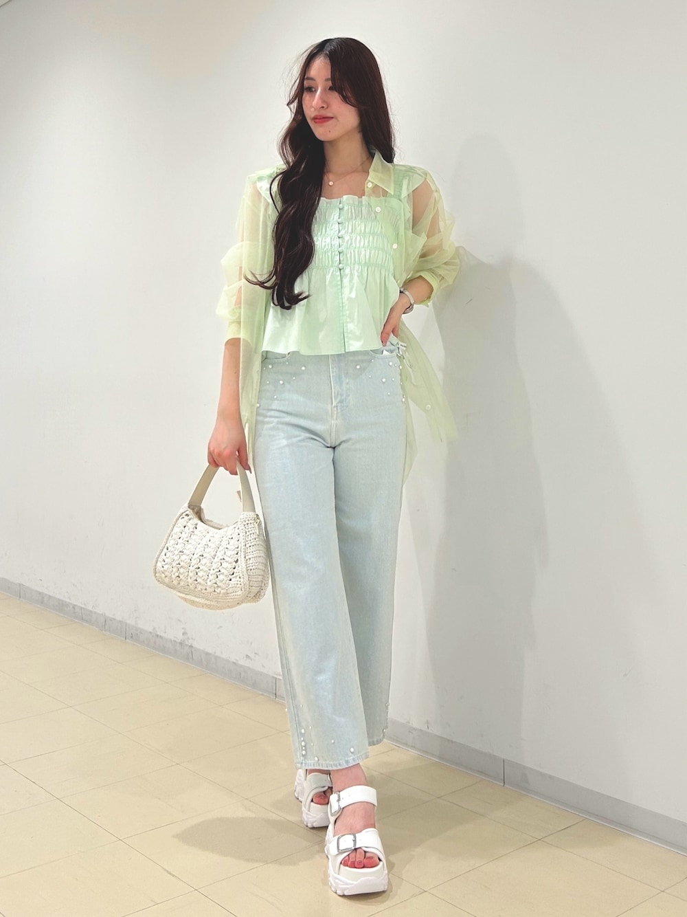 ブルー系のデニムパンツ、グリーン系のシャツ/ブラウス、ホワイト系のショルダーバッグを着用したレディースの春コーディネートの1枚目の写真