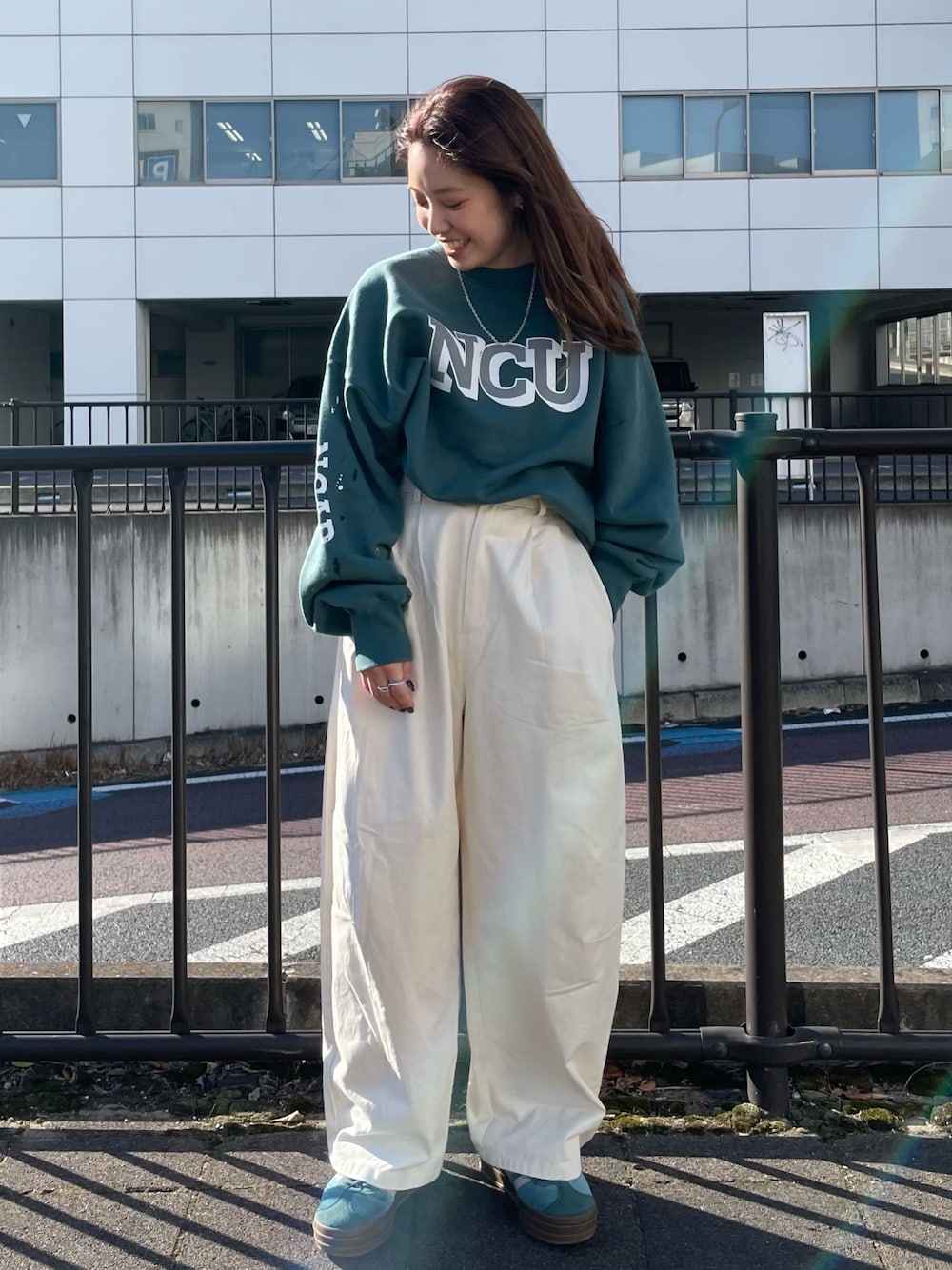 グリーン系のスウェット、ホワイト系のチノパンツを着用したレディースの冬コーディネートの1枚目の写真