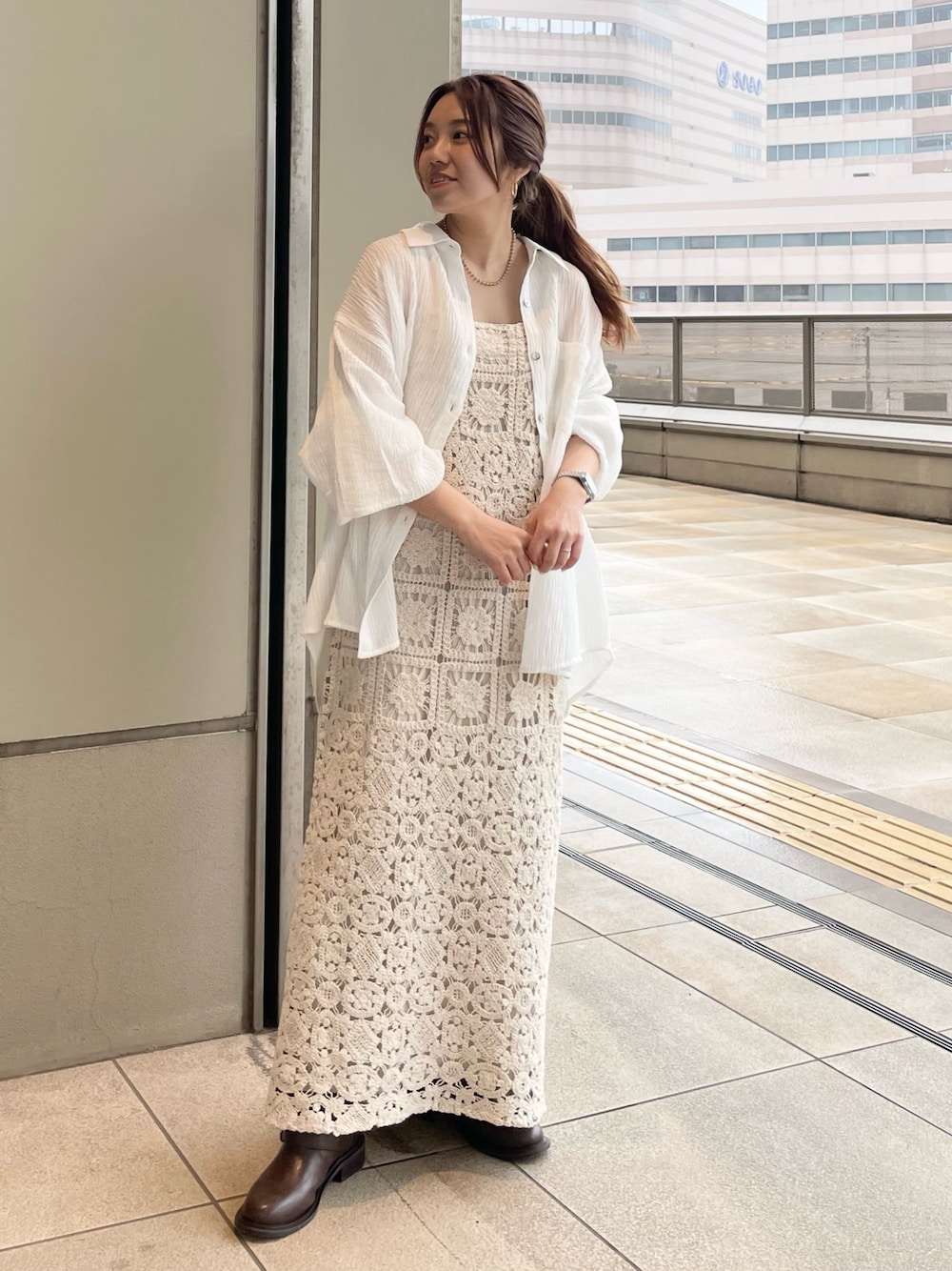 ベージュ系のワンピース、ホワイト系のシャツ/ブラウス、ブラウン系のブーツを着用したレディースの春コーディネートの1枚目の写真
