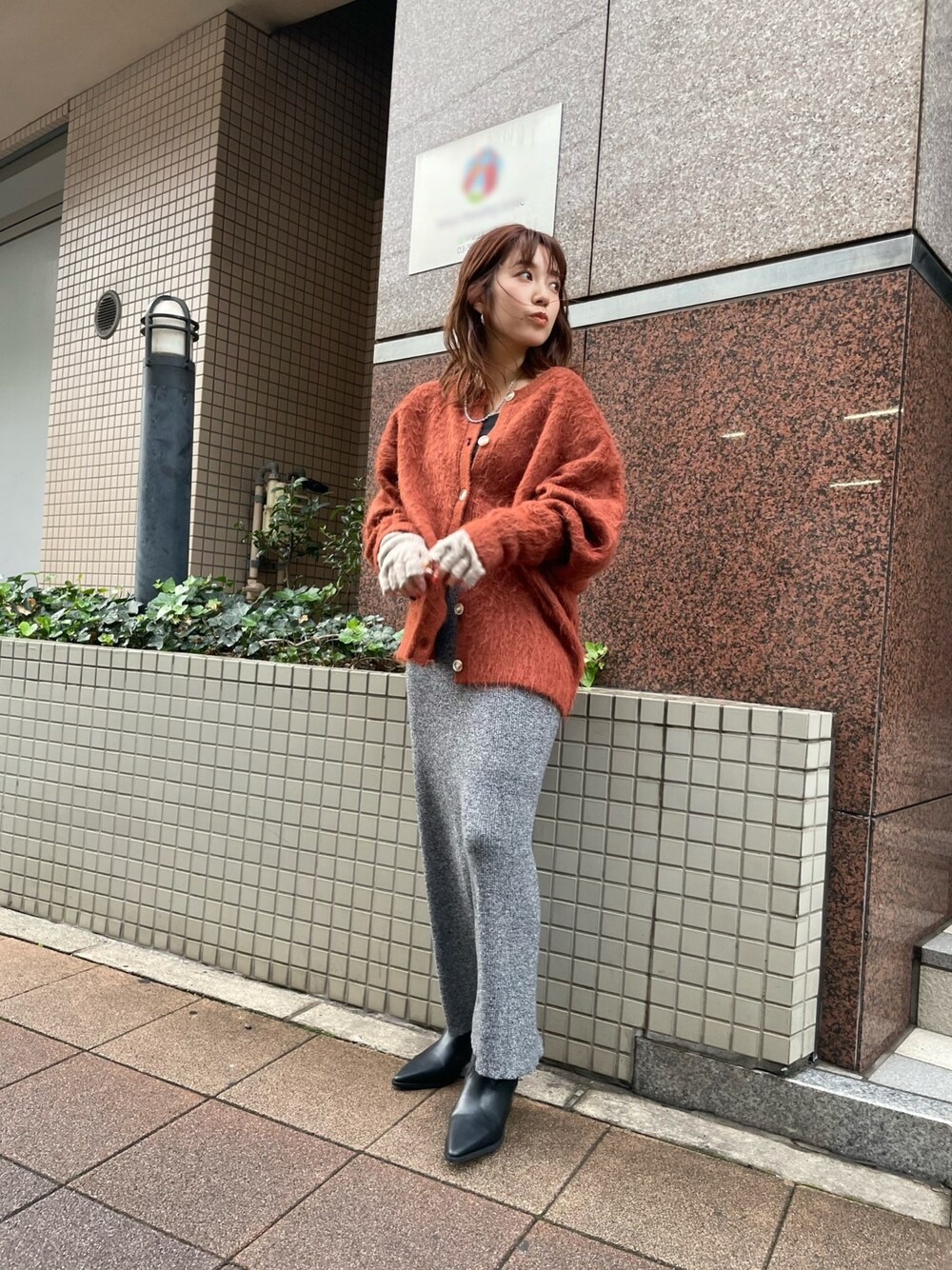 オレンジ系のカーディガン/ボレロ、グレー系のスカート、ブラック系のブーツを着用したレディースの秋コーディネートの1枚目の写真