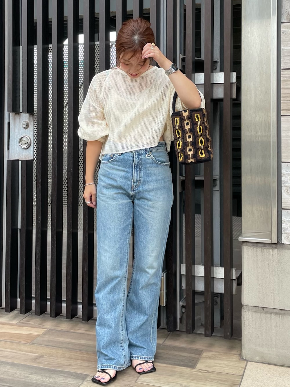 ブルー系のデニムパンツ、ホワイト系のTシャツ/カットソー、ブラウン系のハンドバッグを着用したレディースの夏コーディネートの1枚目の写真