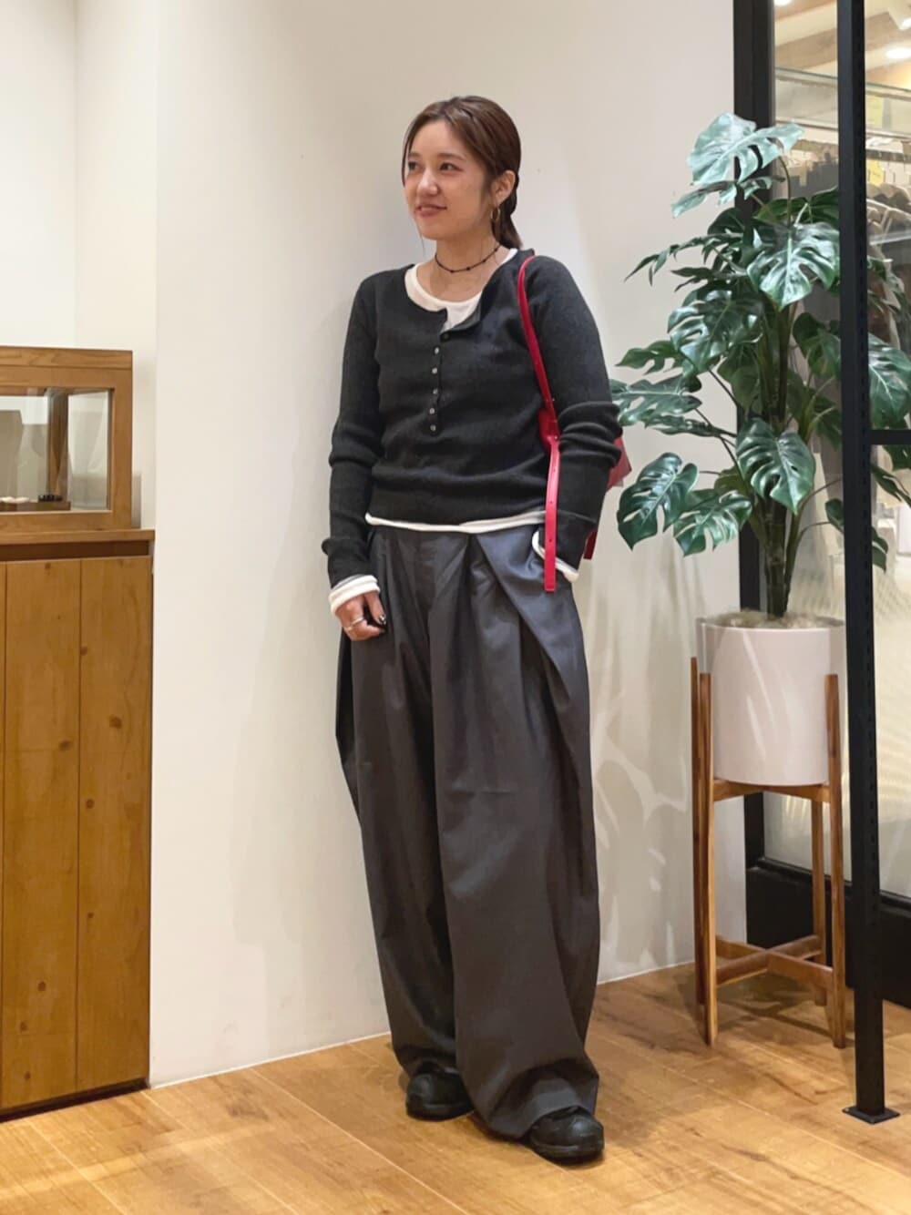 グレー系のニット/セーター、グレー系のその他パンツ、レッド系のハンドバッグを着用したレディースの秋コーディネートの1枚目の写真