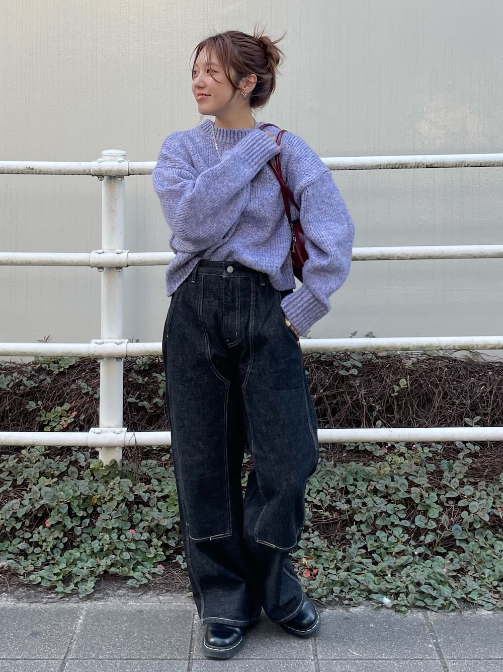 ブラック系のデニムパンツ、パープル系のニット/セーター、レッド系のハンドバッグを着用したレディースの秋コーディネートの1枚目の写真