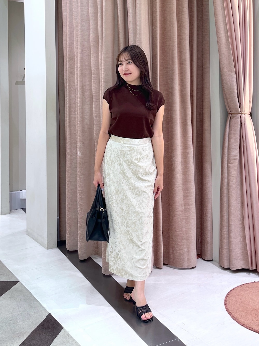 ブラウン系のニット/セーター、ベージュ系のスカート、ブラック系のトートバッグを着用したレディースの夏コーディネートの1枚目の写真