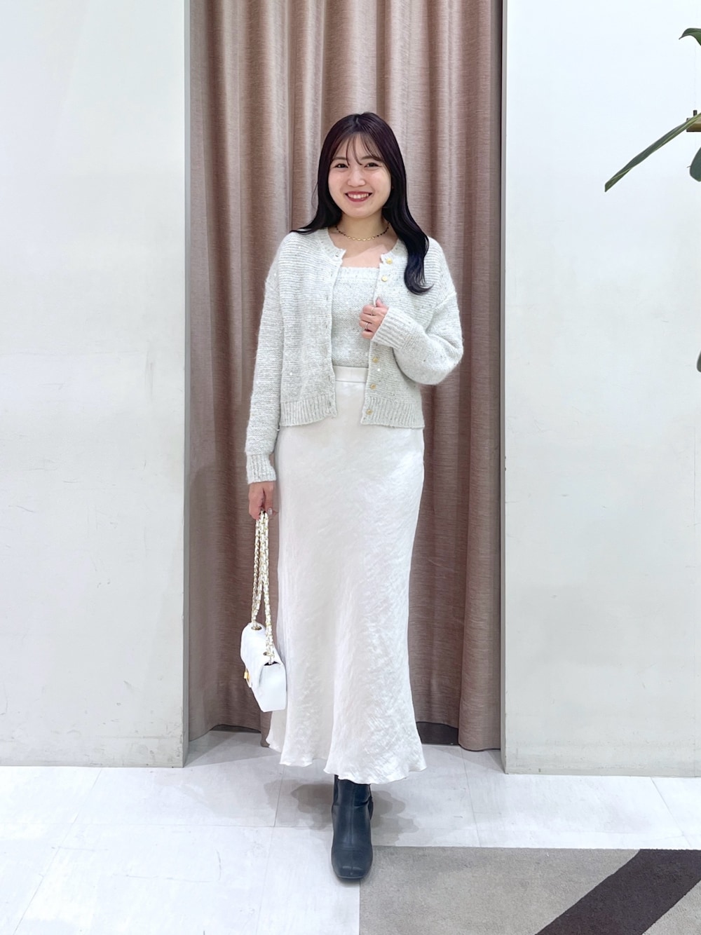 ホワイト系のチューブトップ、ホワイト系のカーディガン/ボレロ、グレー系のスカートを着用したレディースの秋コーディネートの1枚目の写真
