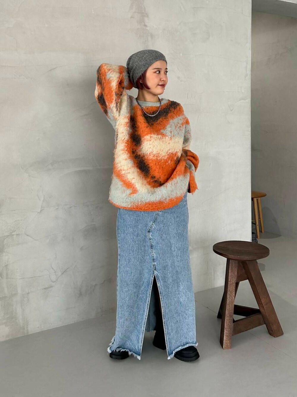 ブラック系のブーツ、オレンジ系のニット/セーター、グレー系のニットキャップ/ビーニーを着用したレディースの秋コーディネートの1枚目の写真