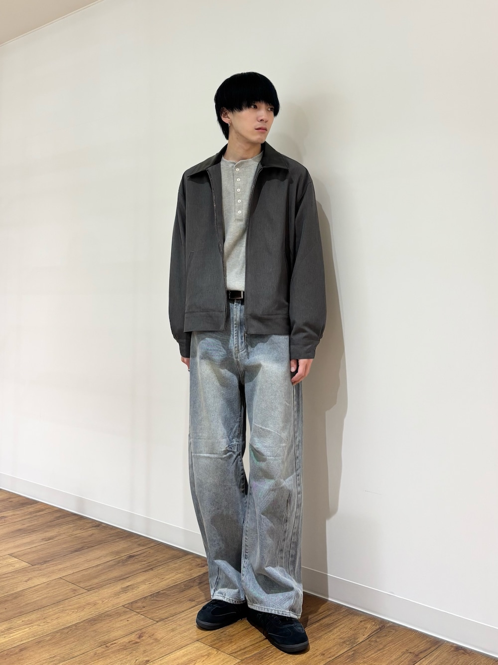 グレー系のブルゾン、グレー系のTシャツ/カットソー、ブルー系のデニムパンツを着用したメンズの冬コーディネートの1枚目の写真