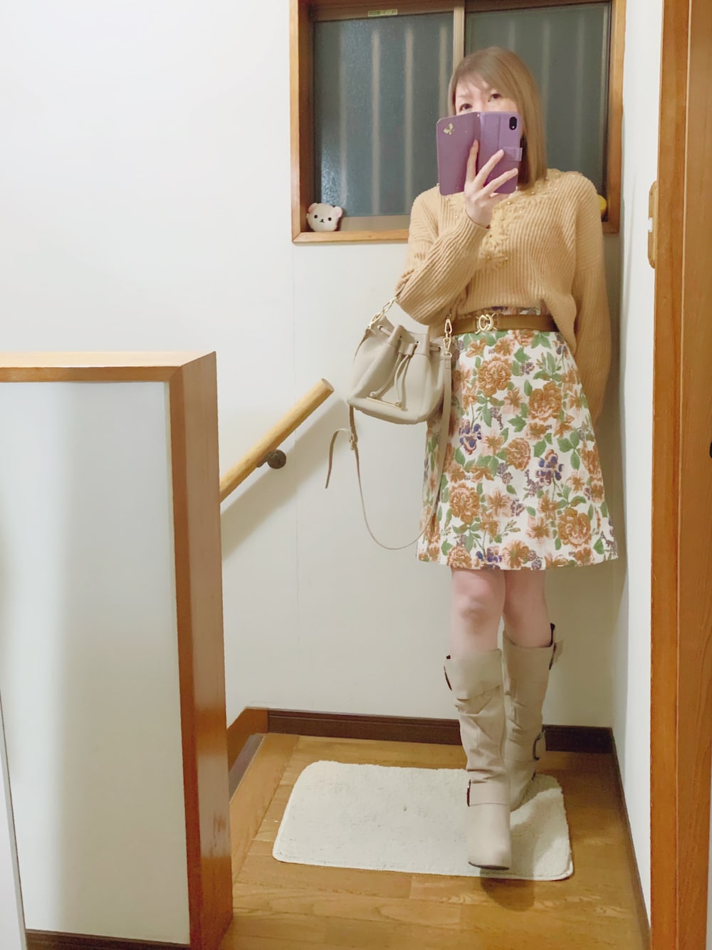ベージュ系のニット/セーター、ベージュ系のショルダーバッグ、ホワイト系のジャケット/アウターを着用したレディースの冬コーディネートの1枚目の写真