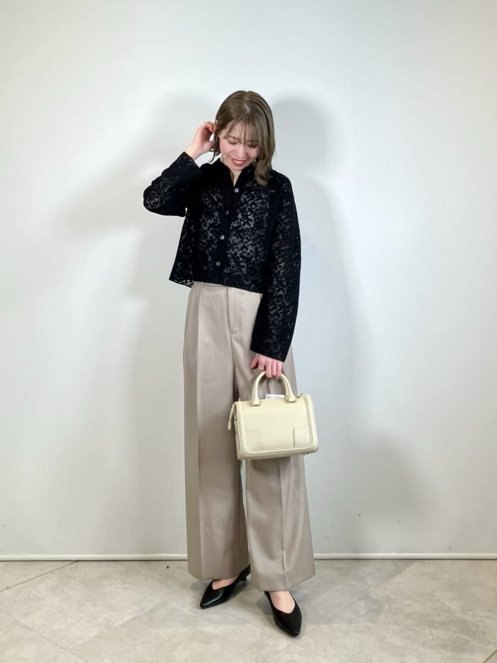 ブラック系のパンプス、ブラック系のカーディガン/ボレロ、ベージュ系のスラックスを着用したレディースの春コーディネートの1枚目の写真