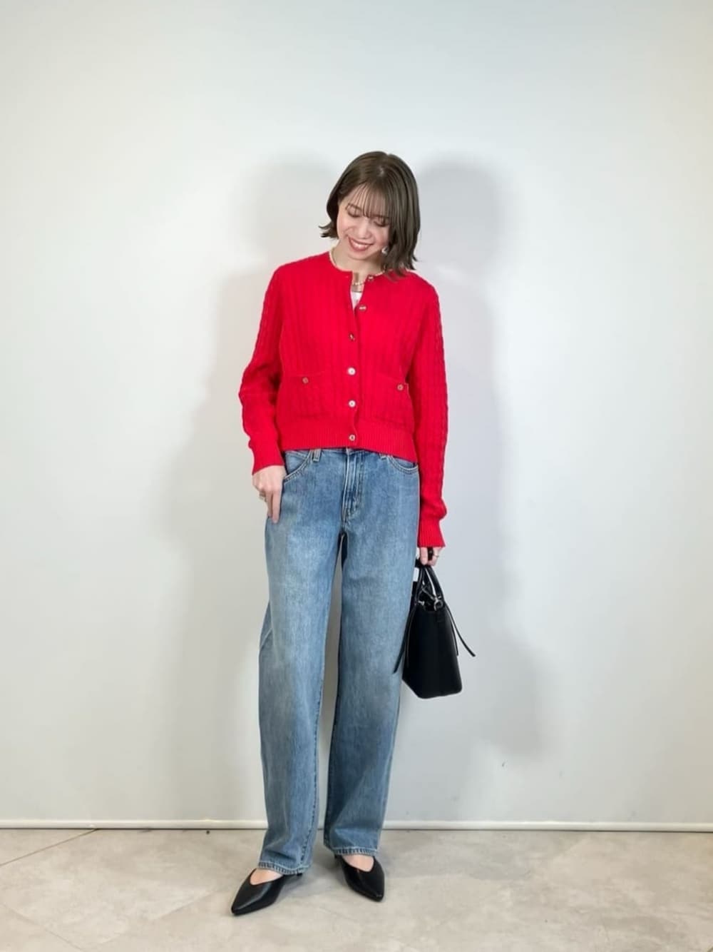 ブラック系のパンプス、ブラック系のショルダーバッグ、ブルー系のデニムパンツを着用したレディースの春コーディネートの1枚目の写真