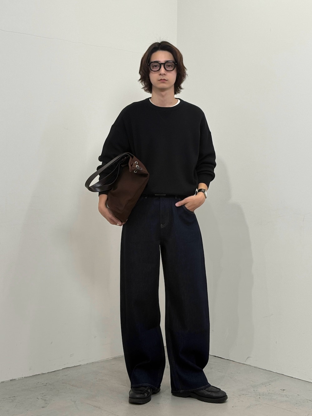 ブラック系のニット/セーター、ブルー系のデニムパンツ、ブラウン系のバッグを着用したメンズの秋コーディネートの1枚目の写真