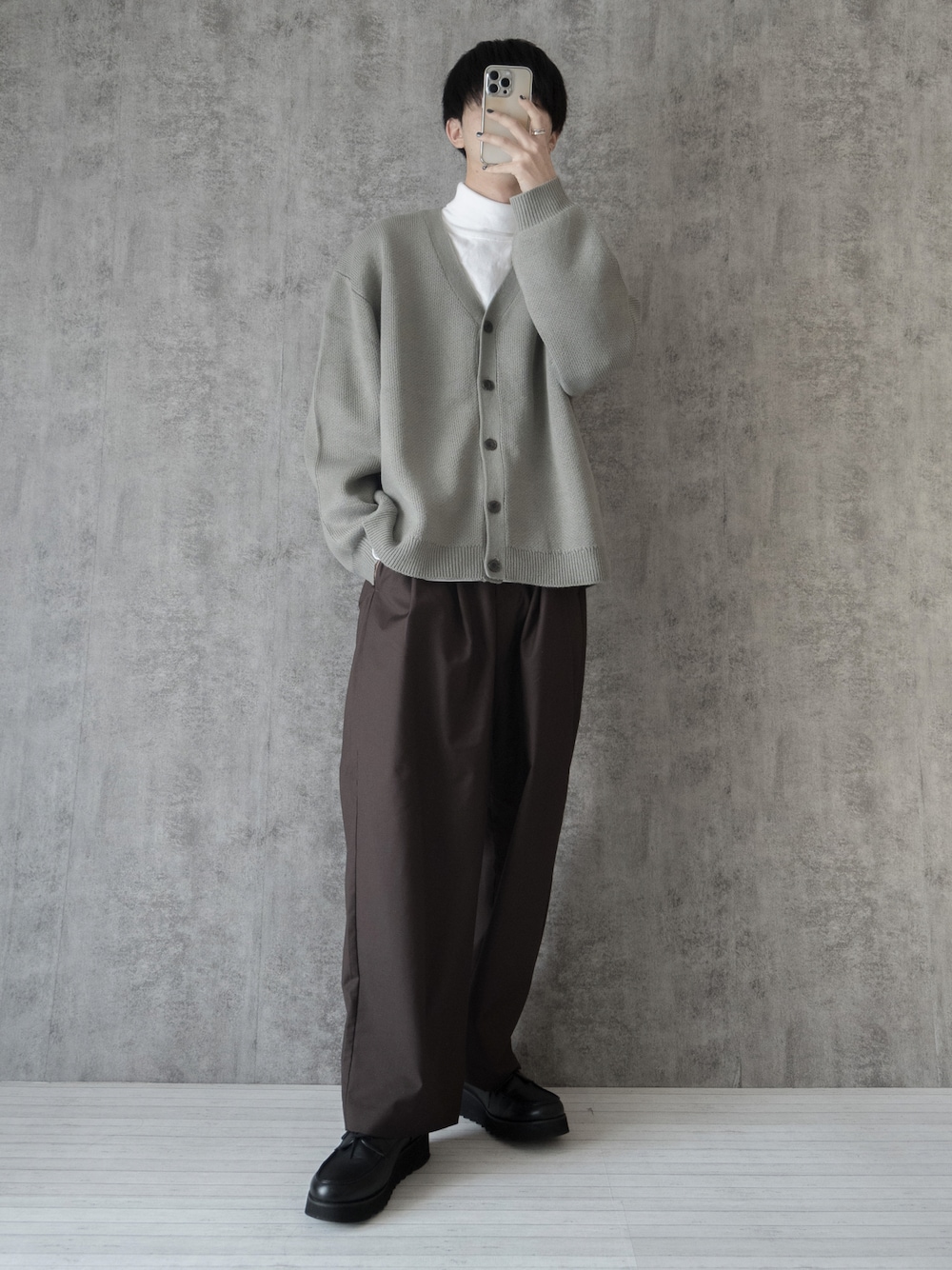 グレー系のカーディガン/ボレロ、ホワイト系のTシャツ/カットソー、ブラウン系のスラックスを着用したメンズの冬コーディネートの1枚目の写真