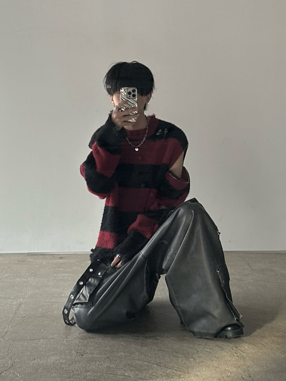 レッド系のニット/セーター、ブラック系のカーゴパンツを着用したメンズの秋コーディネートの1枚目の写真