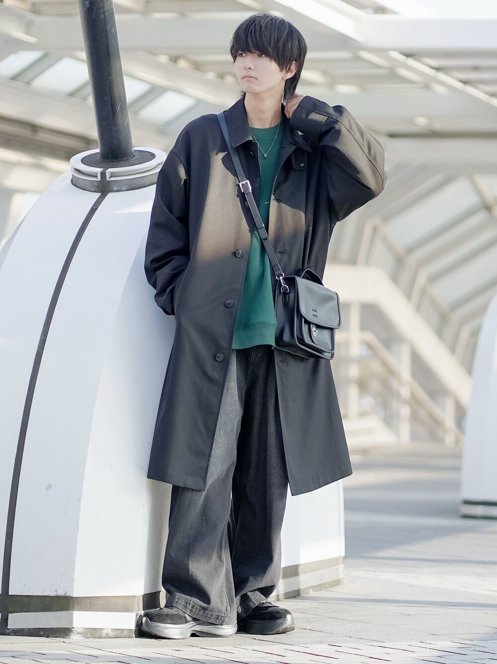 ブラック系のステンカラーコート、グリーン系のスウェット、ブラック系のデニムパンツを着用したメンズの冬コーディネートの1枚目の写真