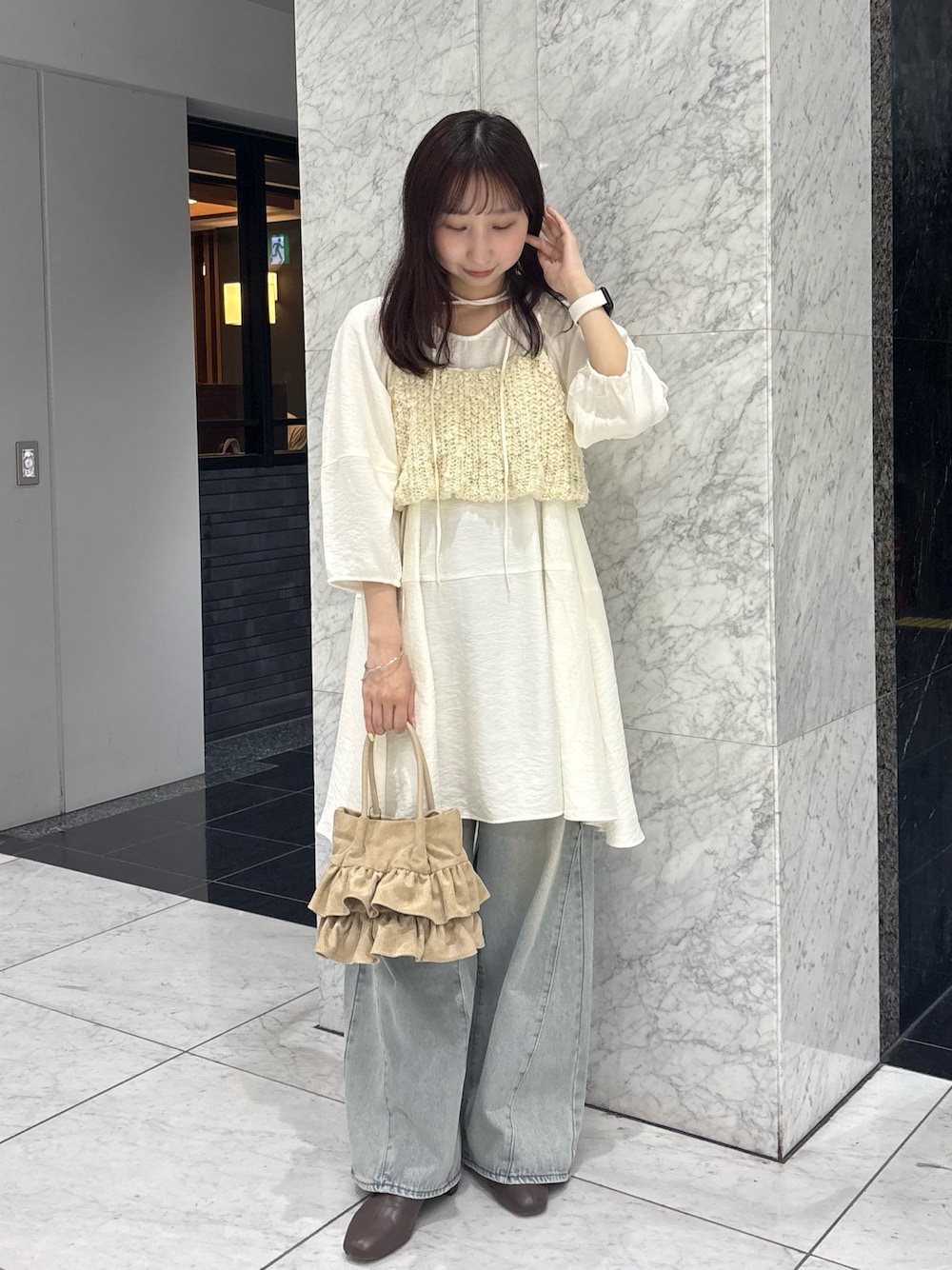 ホワイト系のワンピース、ホワイト系のニット/セーター、ブルー系のデニムパンツを着用したレディースの春コーディネートの1枚目の写真