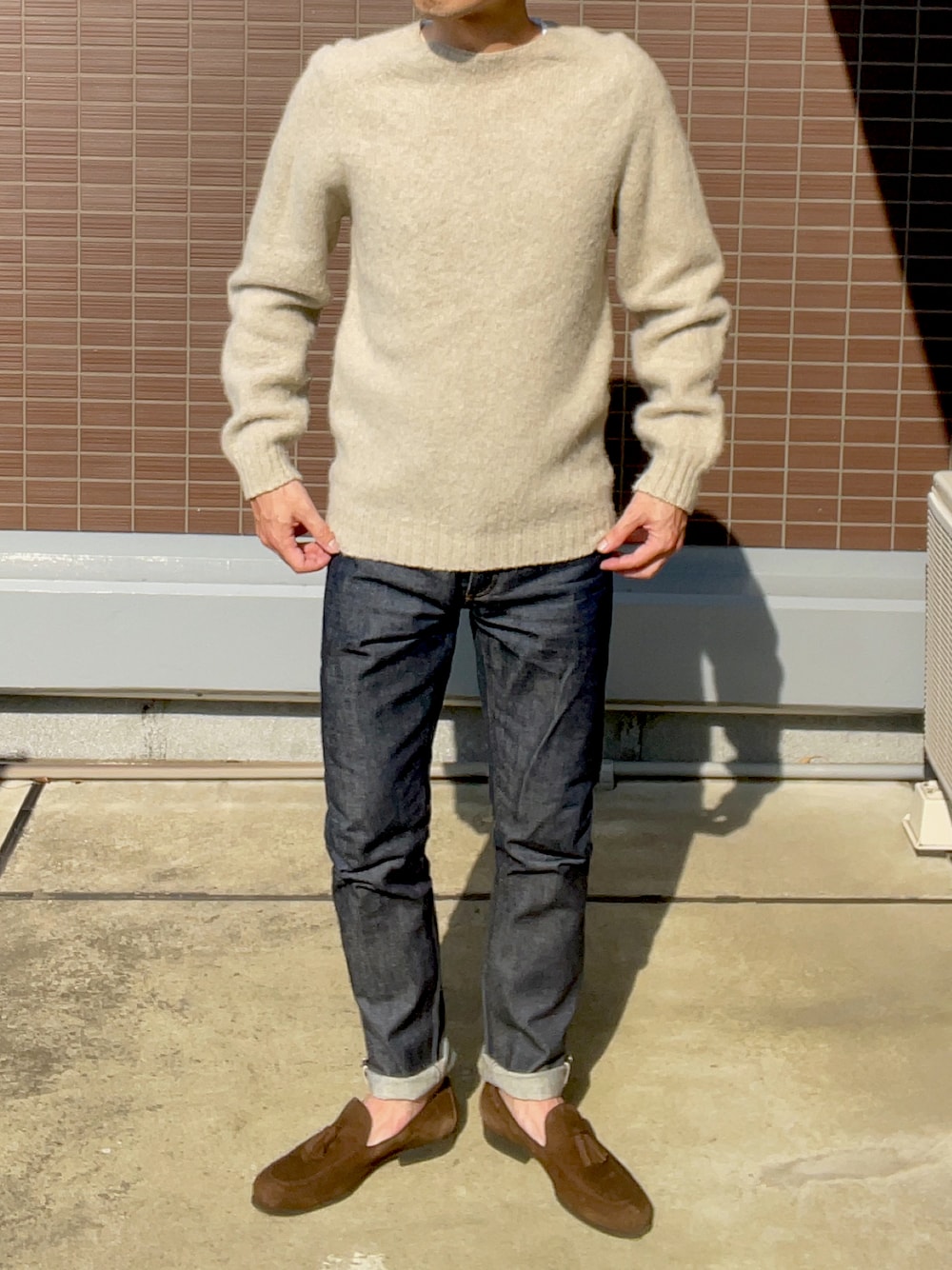 ベージュ系のニット/セーター、ベージュ系のデニムパンツ、ブラウン系のローファーを着用したメンズの春コーディネートの1枚目の写真