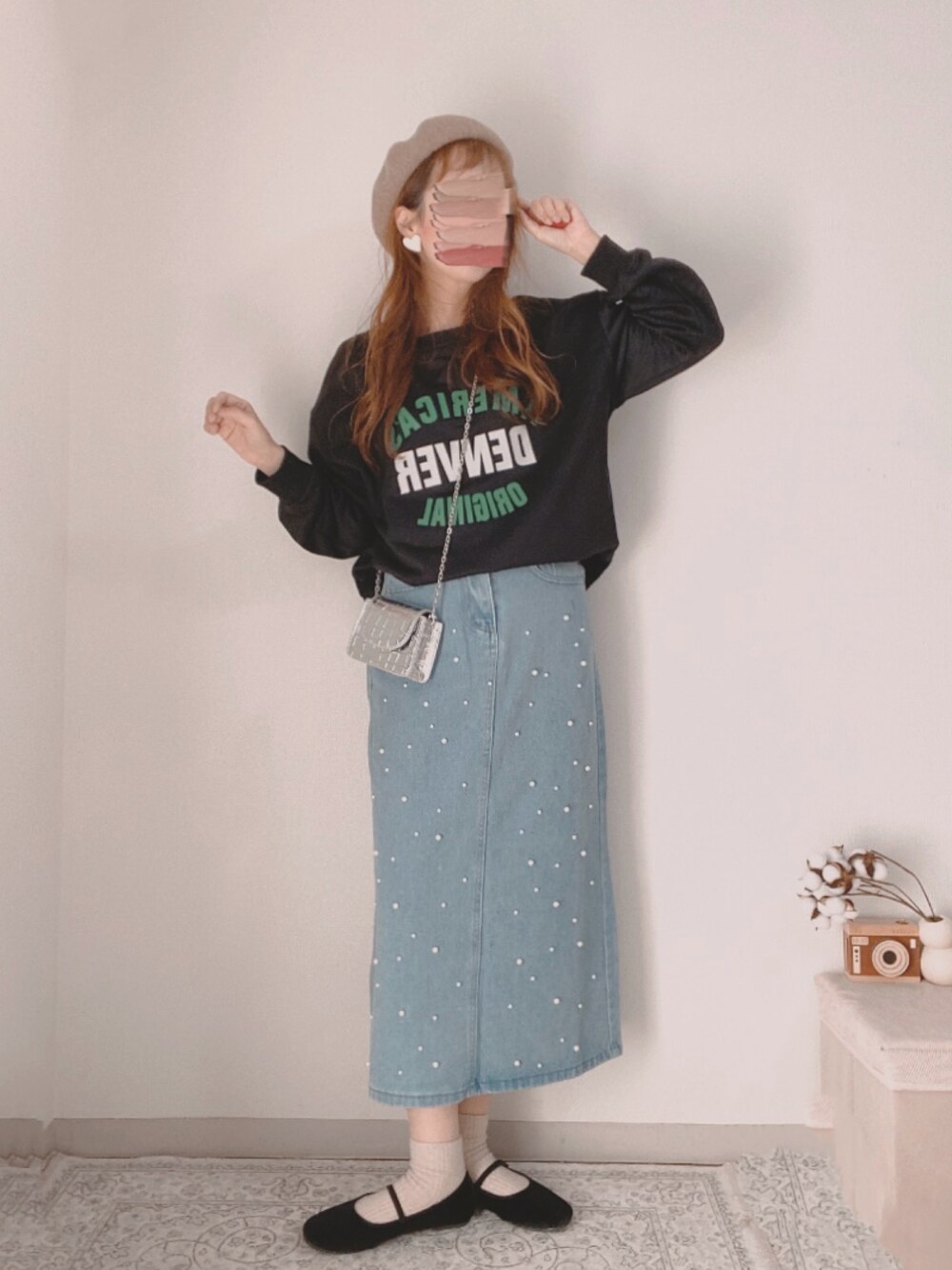 ブラック系のスウェット、ブルー系のデニムスカート、シルバー系のショルダーバッグを着用したレディースの冬コーディネートの1枚目の写真