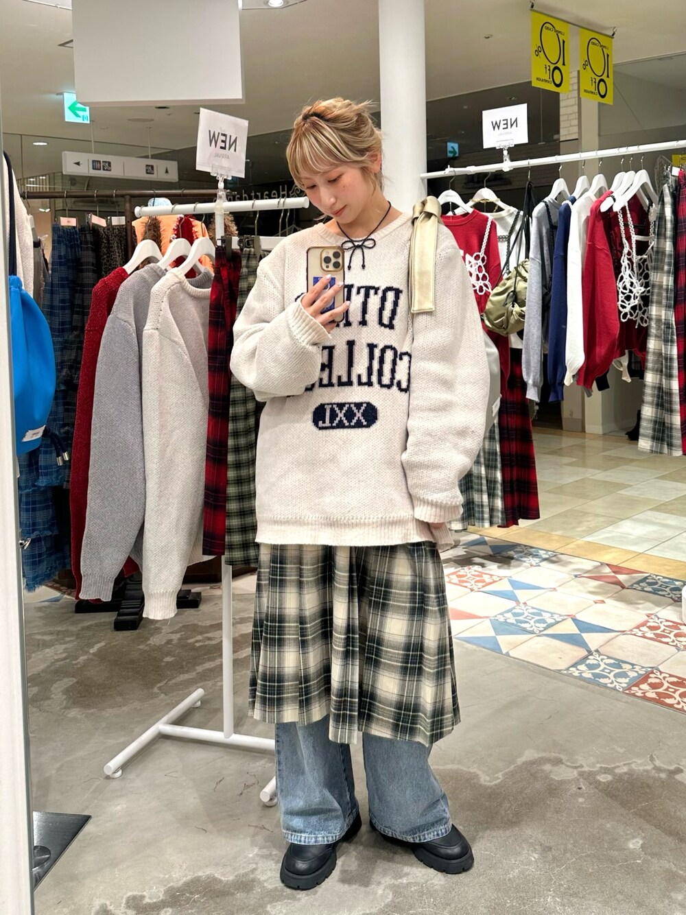 ホワイト系のニット/セーター、ベージュ系のスカート、ブルー系のデニムパンツを着用したレディースの秋コーディネートの1枚目の写真
