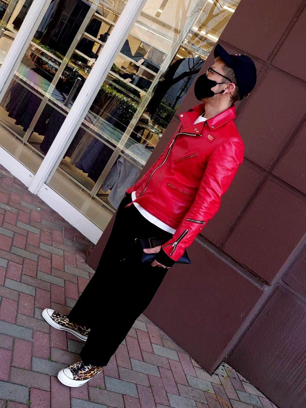 レッド系のライダースジャケット、ブラック系のスラックス、その他のスニーカーを着用したメンズの春コーディネートの3枚目の写真