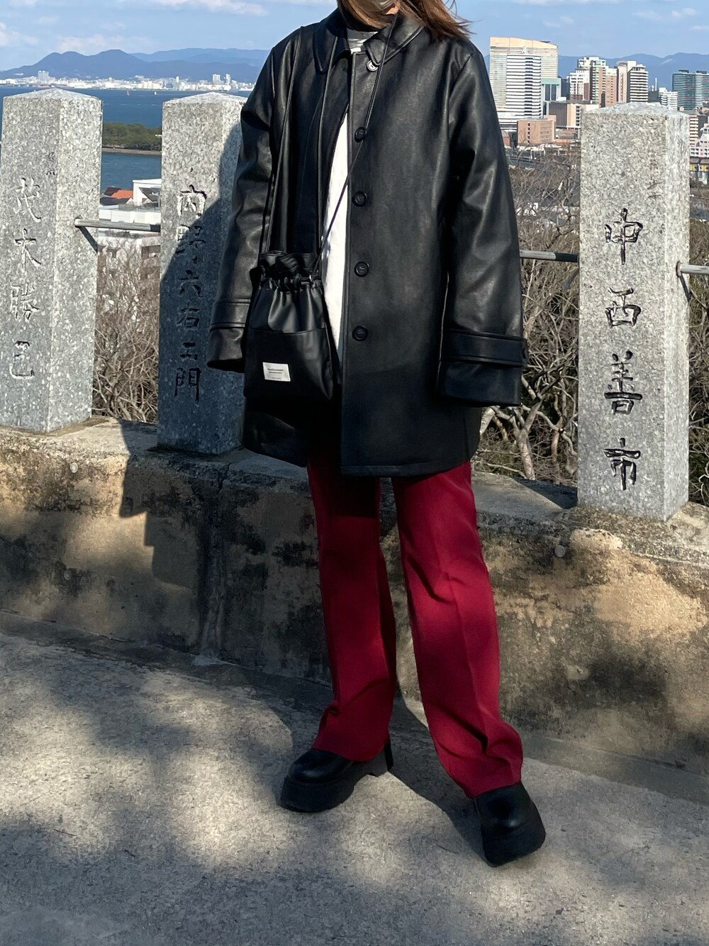 ブラック系のジャケット/アウター、レッド系のスラックス、ブラック系のショルダーバッグを着用したレディースの冬コーディネートの1枚目の写真