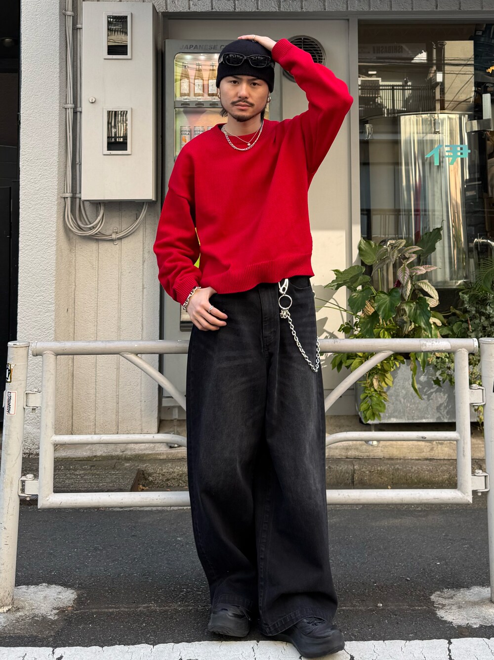 レッド系のニット/セーター、ブラック系のデニムパンツ、シルバー系の財布/小物を着用したメンズの冬コーディネートの1枚目の写真