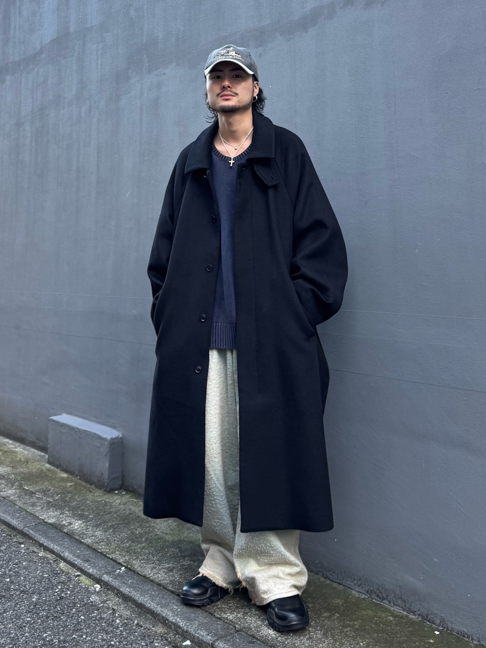 ブルー系のニット/セーター、ブルー系のデニムパンツ、ブラック系のステンカラーコートを着用したメンズの秋コーディネートの1枚目の写真